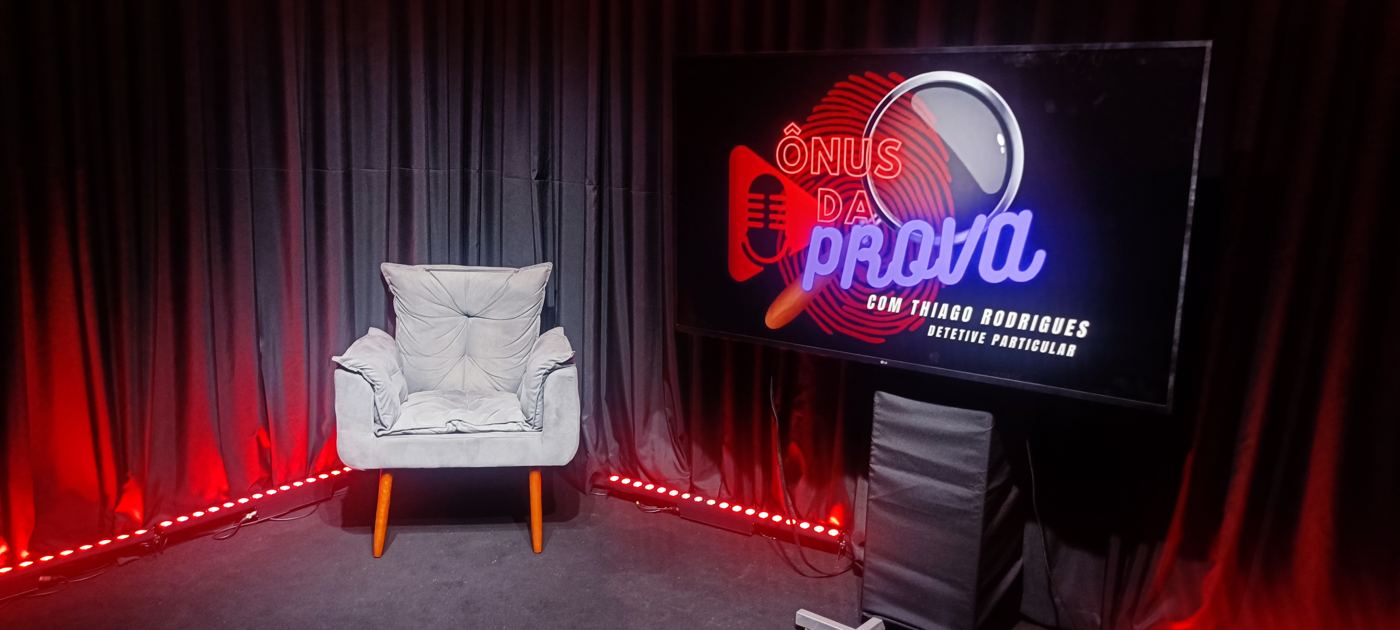 Cenário de podcast com poltrona, cortinas pretas e iluminação vermelha