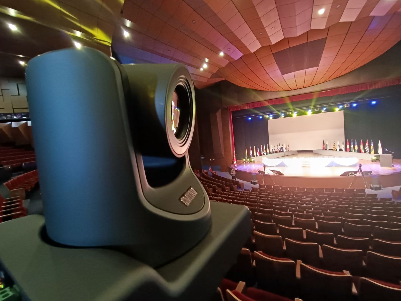 Câmera PTZ em primeiro plano filmando o palco de um grande auditório